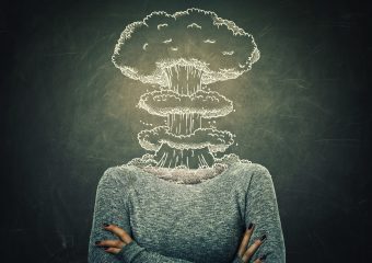 Surreal image young woman head explosion over blackboard background. Mental state of human with lot of problems. Nervous person with crossed hands and a nuclear mushroom sketch, business failure.
